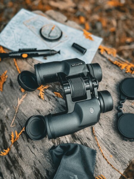 Un binoclu turistic pe un suport din lemn cu o hartă și o busolă în natură. Foto: Rigad