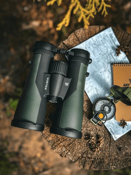 Binoclu de exterior așezat pe un ciot cu o hartă și echipament pentru drumeții. Foto: Rigad