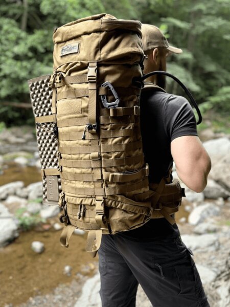 Turist cu un rucsac mare de expediție la un pârâu de munte în pădure. Foto: Rigad