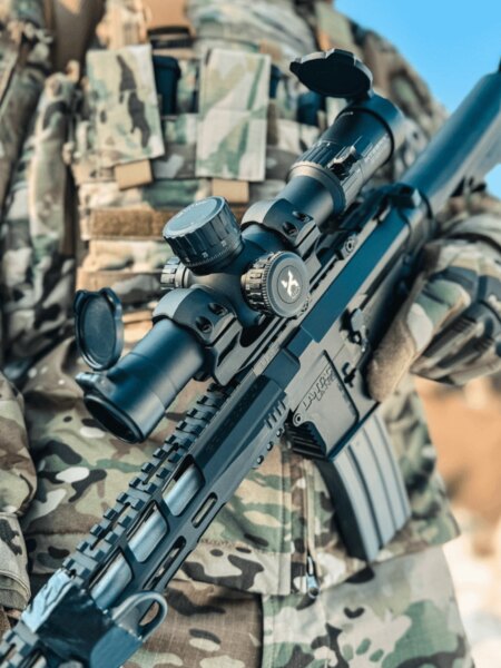 Lunetă Vortex Optics în detaliu pe o pușcă de asalt modernă cu montare pe șină Picatinny, trăgător în ținută de camuflaj. Foto: Rigad