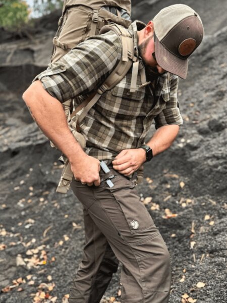 O privire detaliată asupra pantalonilor outdoor Fjällräven în timpul reglării echipamentului pe teren stâncos. Foto: Rigad