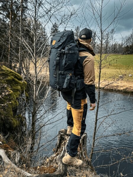 Pantaloni outdoor Fjällräven și un rucsac la malul râului în natură. Foto: Rigad