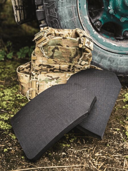 Pereche de plăci balistice curbate (multi-curve) la un purtător în model multicam; mediu exterior lângă roata vehiculului.