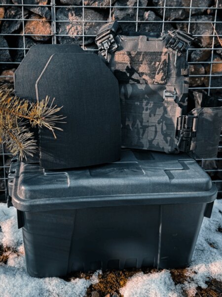 Două plăci balistice în fața suportului pe cutia de transport, mediu de iarnă; exemplu de condiții de funcționare și depozitare.