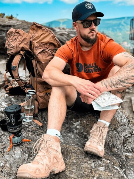 Turist outdoor cu rucsac, șapcă și apă ca protecție împotriva insolației. Foto: Rigad