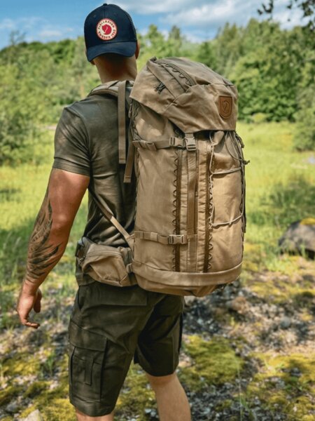 Bărbat cu rucsac și șapcă Fjällräven în drumeție de vară ca prevenire împotriva insolației. Foto: Rigad