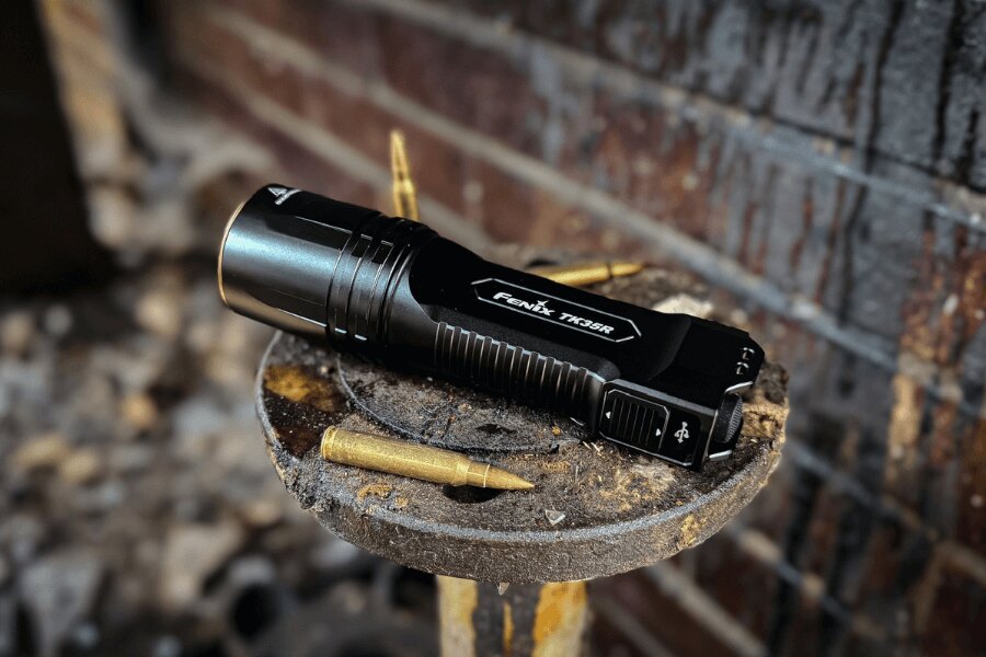 Lanternă tactică de înaltă performanță TK35R Fenix<sup>®</sup> pe o bază metalică cu cartușe. Foto: Rigad