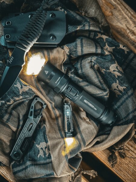 Lanterna tactică P84 NexTorch<sup>®</sup> pe echipament cu un cuțit ANV și echipament EDC. Foto: Rigad