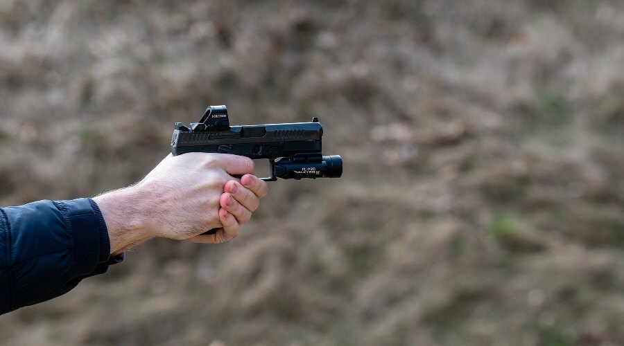 Trăgătorul țintește cu arma în mână