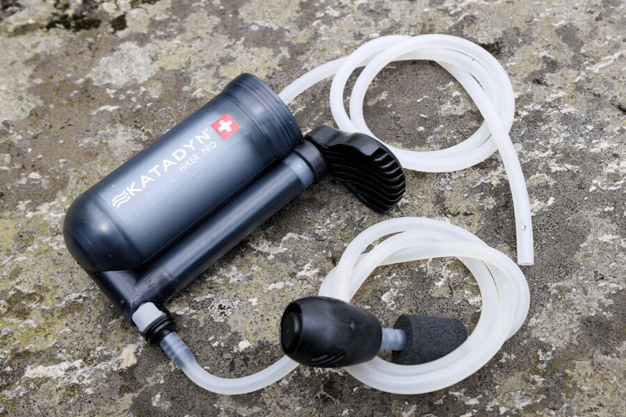 Filtru de apă cu pompă Katadyn Hiker Pro cu furtunuri așezat pe o piatră. Foto: Rigad