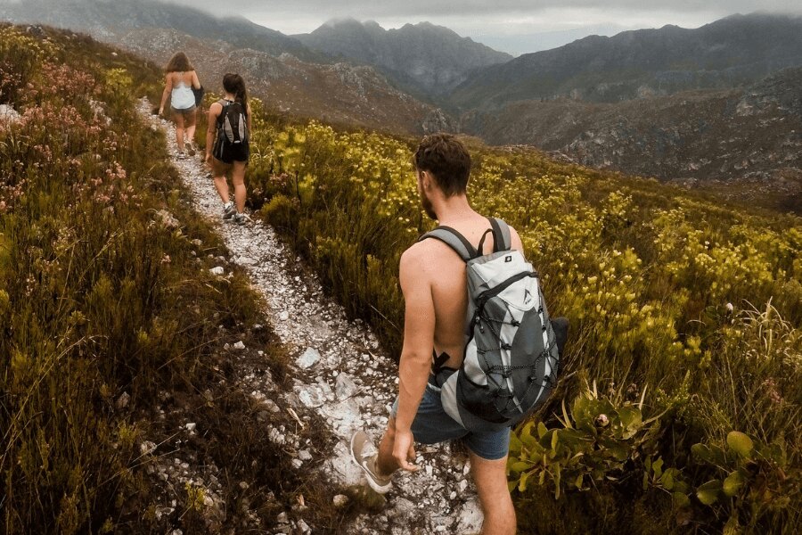 Bărbat fără tricou și două femei pe un drum de munte. Sursa: https://www.pexels.com/cs-cz/foto/930685/