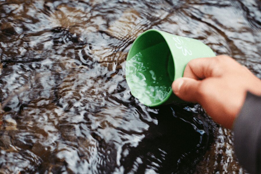 Umplerea cu apă din pârâu în ceașca verde. Sursă: https://www.pexels.com/cs-cz/foto/66090/