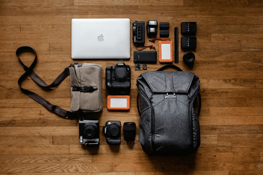 Rucsac despachetat cu aparate foto și electronică. Sursa: https://www.pexels.com/cs-cz/foto/apple-jablko-chytry-telefon-notebook-3178938/