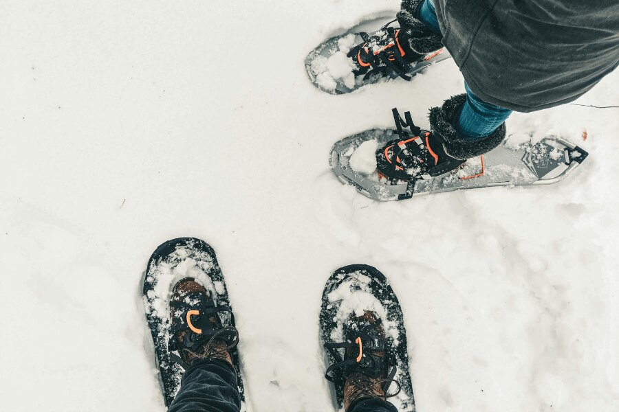 Două perechi de picioare în rachete de zăpadă. Sursa: https://www.pexels.com/cs-cz/foto/ryma-studeny-snih-lide-10772331/