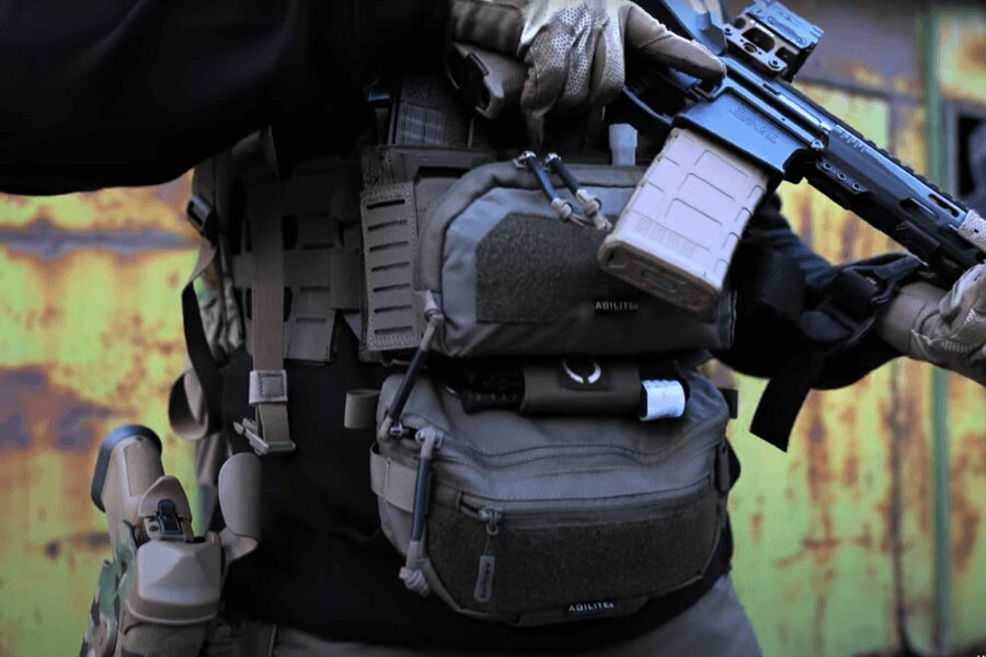 Bărbat cu Chest Rig Reaper™ Agilite Gear® echipat cu pungi și cu o armă lungă. Sursa: Rigad - video