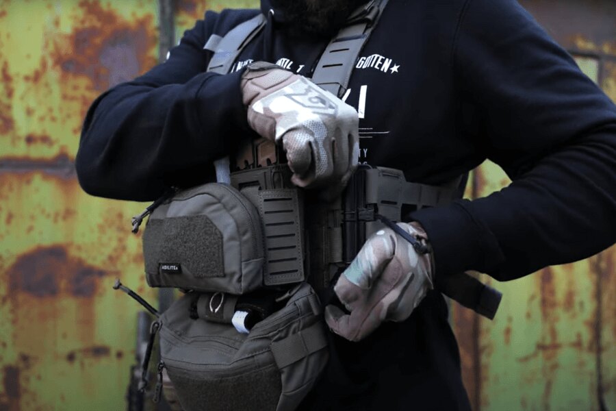 Bărbatul cu Chest Rig Reaper™ Agilite Gear® echipat cu pungi ajustează setările. Sursa: Rigad - video