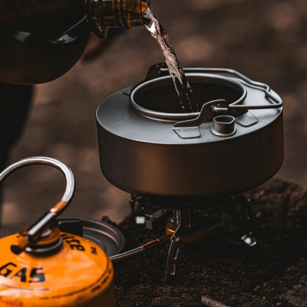 Gătit în aer liber în natură. Sursa: https://www.pexels.com/cs-cz/foto/voda-misa-kempovani-lahev-20397578/