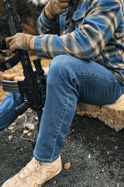 Bărbat în pantaloni Treadstone Jeans® Helikon-Tex® cu o cămașă în carouri și cu o pușcă. Foto: Rigad