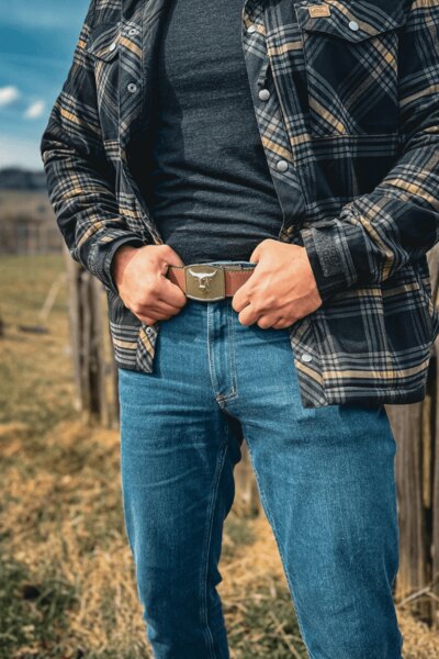 Bărbat în pantaloni Treadstone Jeans® Helikon-Tex® într-o cămașă în carouri se ține de curea. Foto: Rigad