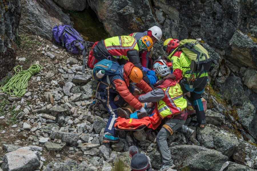 Echipa de salvare montană stabilizează rănitul în timpul evacuării în teren stâncos. Foto: https://www.pexels.com/cs-cz/foto/skupina-zachranaru-zachranujicich-zranenou-osobu-na-rocky-mountainside-9424563/
