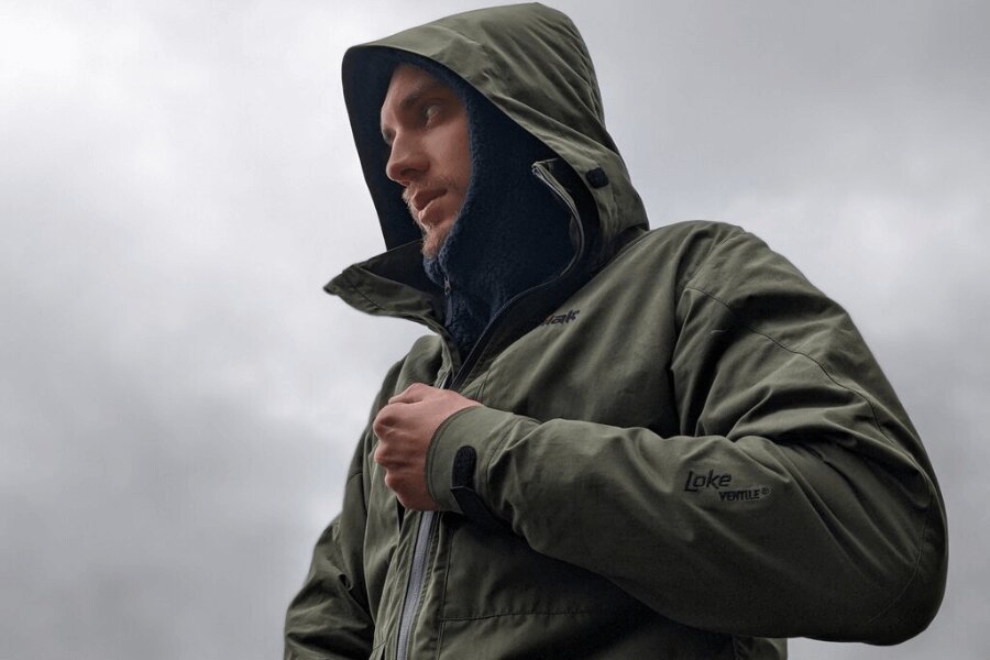 Tilak Loke 24 cu Ventile® în culoarea măsliniu, cu glugă atașată, închidere cu fermoar impermeabil; protecție silențioasă și respirabilă pentru ploaie. Foto: Rigad