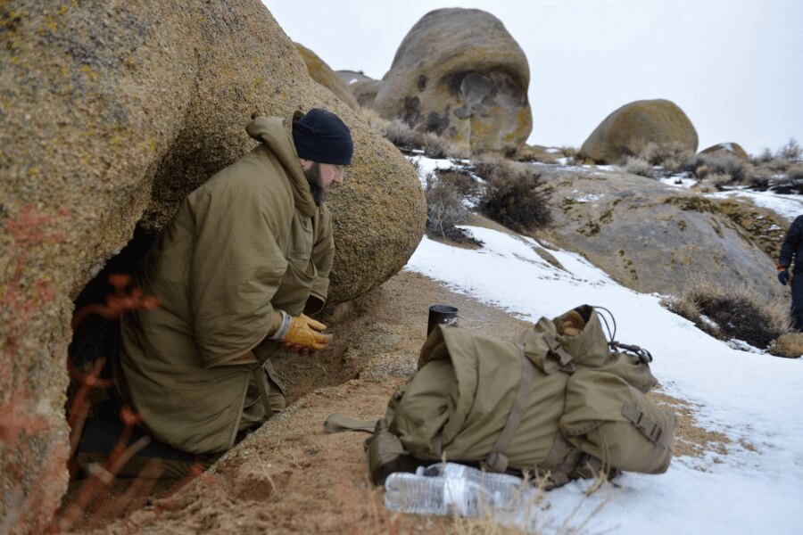 Campare de urgență pe timp de iarnă în teren – utilizarea unei stânci ca adăpost natural împotriva vântului și frigului. Foto: Helikon-Tex, Rigad