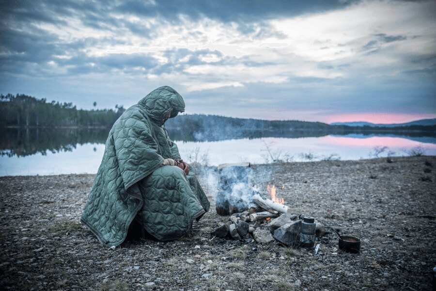 Izolație de urgență iarna - utilizarea unei pelerine izolate la campare în aer liber în condiții reci. Foto: Helikon-Tex, Rigad