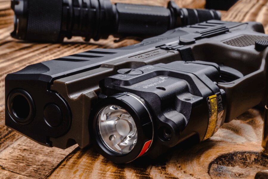 Detaliu pistol negru cu lanternă LED submontată și montare pe șina Picatinny – Foto: Rigad