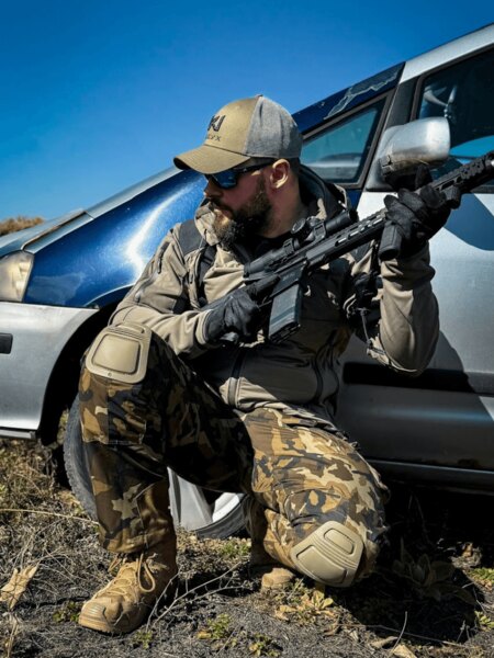 pantaloni tactici Red Dot One Alpha II cu protecții pentru genunchi în poziția de tragere pe teren – Foto: Rigad