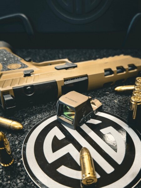 Colimator SIG Sauer ROMEO-X pentru pistoale așezat în fața pistolului SIG Sauer și a muniției de 9 mm. Foto: Rigad