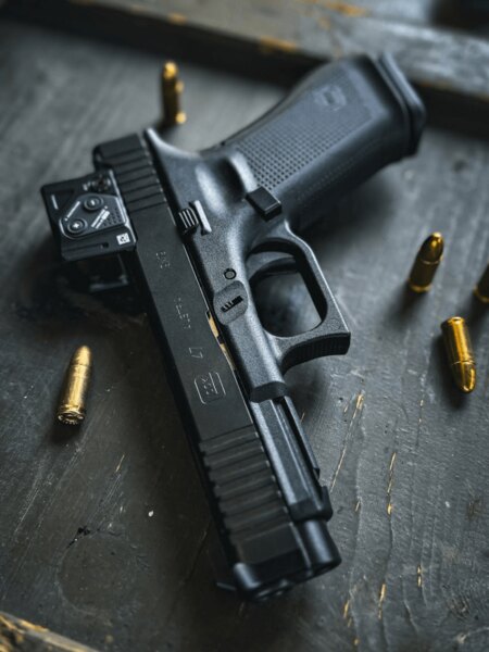 Glock 47 cu colimator Aimpoint COA pe A-CUT, detaliu al pistolului cu gloanțe pe masă, Foto: Rigad