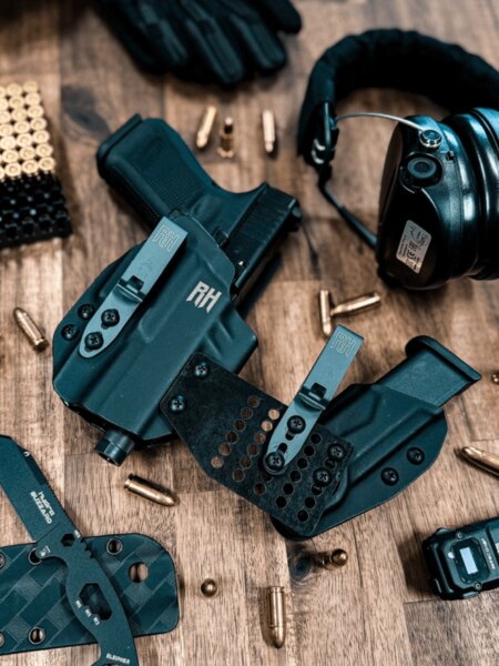Tocuri IWB din Kydex pentru pistol cu cleme și echipament EDC pe o masă de lemn.