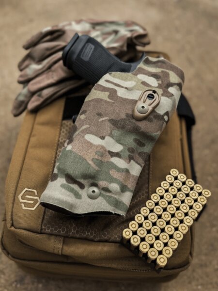 Cartușe calibru 9 mm Luger lângă pistol în toc de camuflaj pe echipamentul de tir.