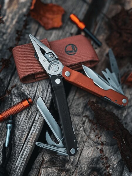 Instrument multifuncțional Leatherman Rebar cu cleștele deschis și uneltele extinse pe o suprafață de lemn.