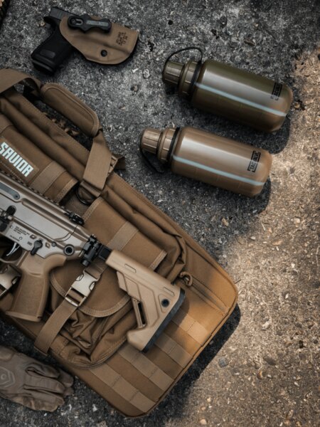 Două sticle de apă TacValve<sup>®</sup> ModCan lângă echipamentul de tragere și pușca semiautomată.