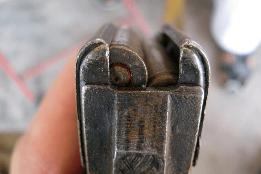 Detaliu al părții superioare a unui încărcător de oțel uzat pentru AK-47 cu cartușe calibru 7,62 × 39 mm.