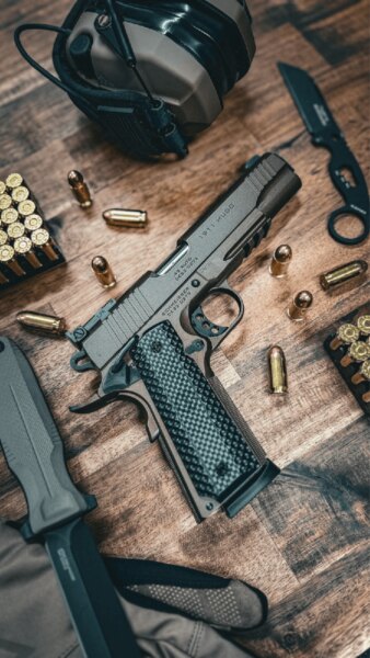 Pistol Schmeisser HUGO 1911 5" în calibru .45 ACP așezată pe masă cu muniție și echipament de tir.