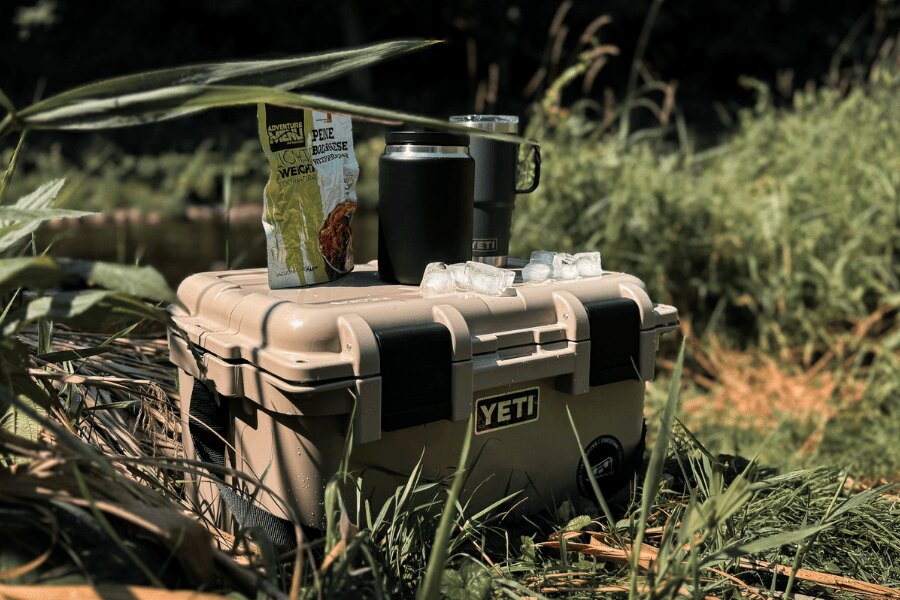 Cutie de transport YETI LoadOut GoBox cu mâncare ambalată și termosuri în natură.