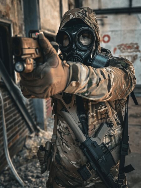 Un trăgător cu o mască de protecție integrală pe față cu filtru țintind cu un pistol.
